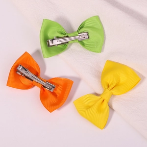Detailed view of three ribbed ribbon bow hair clips in green orange and yellow colors