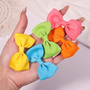 Close-up of five colorful ribbed grosgrain ribbon bow clips held in hand for scale