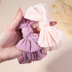Gros plan de bandeaux jacquard en tricot rose et violet avec nœuds 3D pour bébés