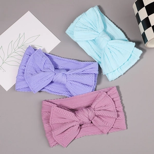 Detail of three-color baby nylon headbands showing elastic ribbed knit texture and soft bows