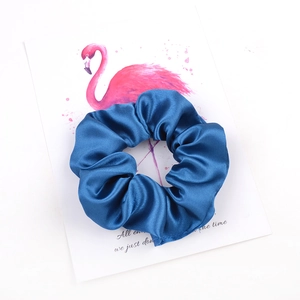Chouchou en satin bleu marine sur carte flamant rose pour coiffures élégantes