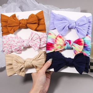 Detailed view of elastic cable knit nylon baby headbands with large fabric bows in diverse colors