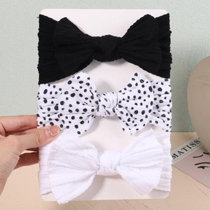 Detail of 3-pack baby nylon headbands featuring large bows in black, white, and polka dots