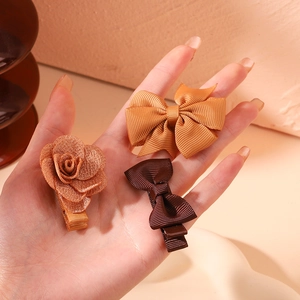 Detail of handmade fabric hair clip set including bows and a rose on a palm