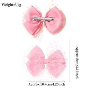 Detail showing two pink polka dot mesh bow hair clips with stainless steel clips
