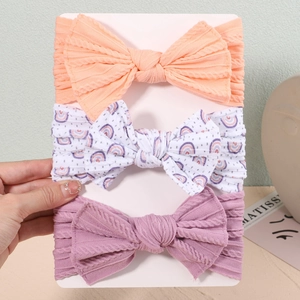 Three-piece baby bow headband set showing soft knitted elastic texture and colors