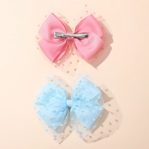 Close-up of pink and blue mesh bow hair clips with polka dots and silver metal crocodile clips
