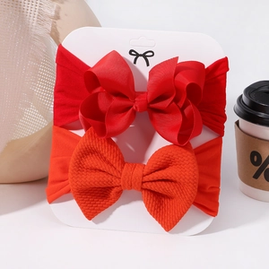 Detail of red grosgrain bow and orange waffle texture bow on soft white elastic nylon headbands