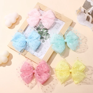 Close-up of five colorful mesh bow hair clips with polka dots on a wooden background