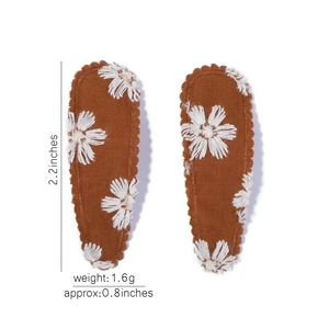 Détail de barrettes BB en toile caramel avec broderie marguerite et bords en zigzag