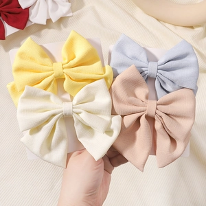 Détail de barrettes à nœuds en satin pastel sur un fond de tissu doux et texturé