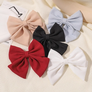 Vue détaillée des barrettes à nœuds en satin de qualité en ivoire, bleu, noir, rouge et blanc