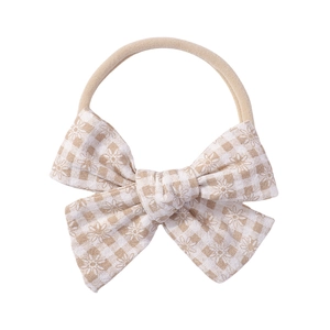 Detailed macro of baby nylon headband with plaid bow and daisy floral print patterns
