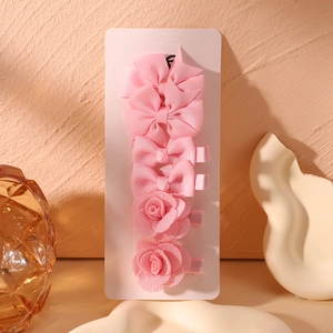 Detail of 6-piece pink fabric hair clips set including bows and roses on card