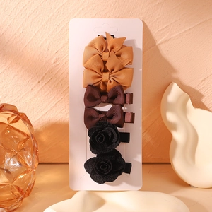 Detailed view of 6-piece handmade fabric hair clips set on card with ribbon bows and roses