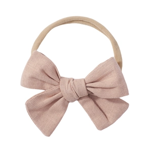 Close-up of pink linen bow texture on a nude nylon elastic baby headband detail