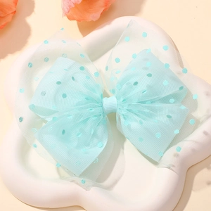 Detail of light blue mesh bow hair clip with dark blue polka dots on a cloud tray