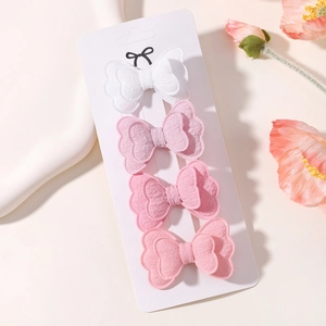 Detailed view of four layered fabric butterfly hair clips in gradient shades of pink and white