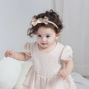 Detailed view of beige ribbed fabric bow headband on infant model with soft natural lighting
