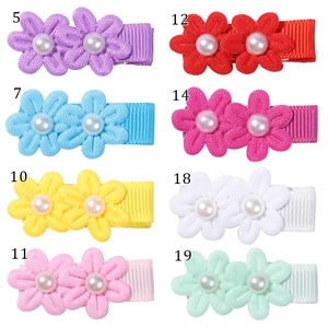 Dettaglio di fermagli per capelli a fiore in tessuto con perle in vari colori e trame