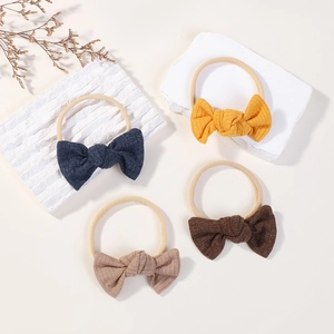 Set of four textured knit bow headbands in yellow, navy, brown, and beige for babies