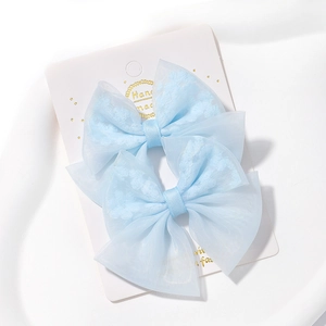 Détail de barrettes à nœuds en résille bleu clair faites à la main sur carte blanche