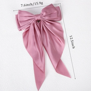 Macro detail of large pink satin bow hair clip with 7.6 inch width and 12.5 inch long ribbons