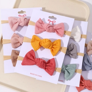 Close-up of baby bow headbands in various colors on white display cards for sale