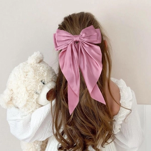 Large dusty rose satin bow hair clip with long ribbons on wavy hair from back view