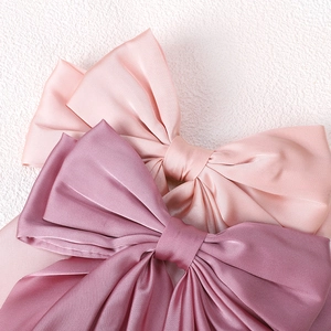 Close-up of pink and purple oversized satin bow hair clips with a silky finish