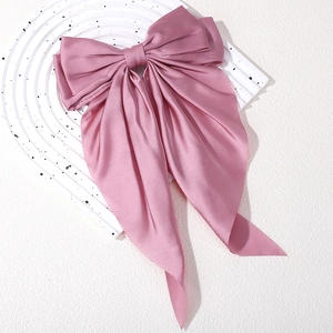 Detailed macro view of dust pink satin bow hair clip with smooth silky texture and shine