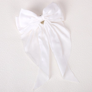 Detailed shot of large white satin bow hair clip with elegant long ribbon tassels