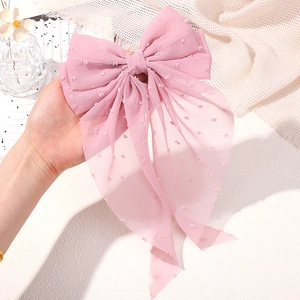 Close-up of pink Swiss dot chiffon bow hair clip with long streamers and textured fabric