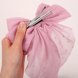 Detail view of the metal alligator clip on a pink mesh bow hairpin with 3D dots