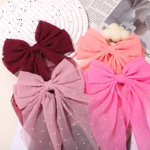 Close-up of chiffon bow hair clips with Swiss dots and elegant long ribbons in four pink shades