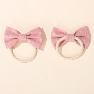 Detail view of pink fabric bow hair ties with high-elasticity beige bands for girls