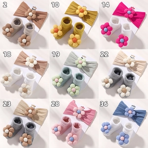 Detailansicht von Baby-Stirnband und Socken mit dreilagigen Stoffblumen und Perlenakzenten