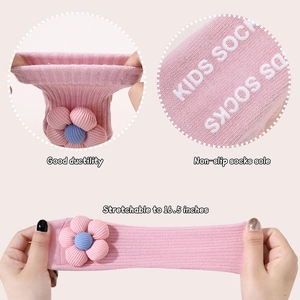 Detail von rosa gestrickten Babysocken mit rutschfester Sohle und 3D-Blumenakzenten