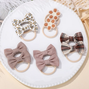 Detail of five assorted bow hair ties with floral and knit patterns on a white tray