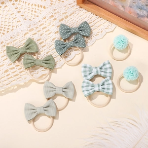 Close-up of green bow hair ties set with polka dots and stripes on beige background