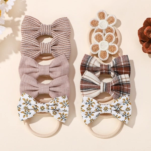 8-piece set of baby bow hair ties featuring floral patterns and solid colors on beige