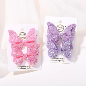 Dettaglio di fermagli per capelli a farfalla glitterati in rosa e viola su card