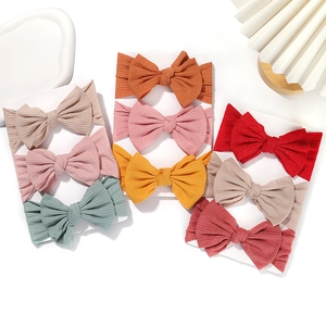 Elastic knitted baby headbands set with large fabric bows in various vibrant colors