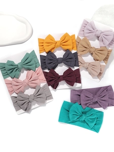 Detailed macro view of soft ribbed knit baby headbands with large bows in multiple colors