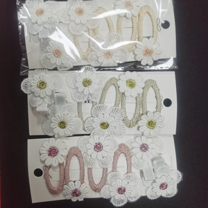 Detailed view of handmade daisy flower hair clips with lace embroidery and woven fabric textures