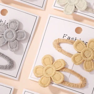 Detail van geborduurde madeliefje haarspelden in zachte pastelkleuren op kaarten