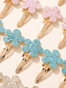 Fermagli per capelli a fiori glitterati in blu, rosa e oro mostrati in dettaglio ravvicinato