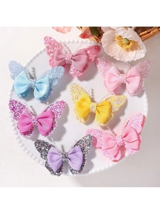 Detail of glitter butterfly hair clips set with ribbon bows and beads in a ceramic tray
