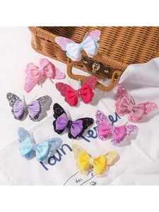Detail showing colorful glitter butterfly hair clips with ribbon bows on a white bag