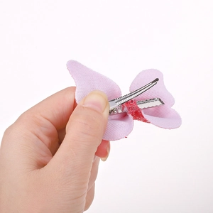 Dettaglio di fermaglio per capelli a fiocco rosa con centro glitterato e clip a becco d'anatra